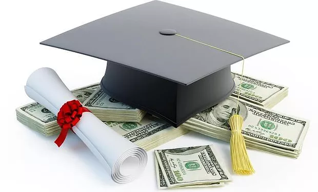 A graduation cap and a diploma sitting on top a pile of 100 dollar bills